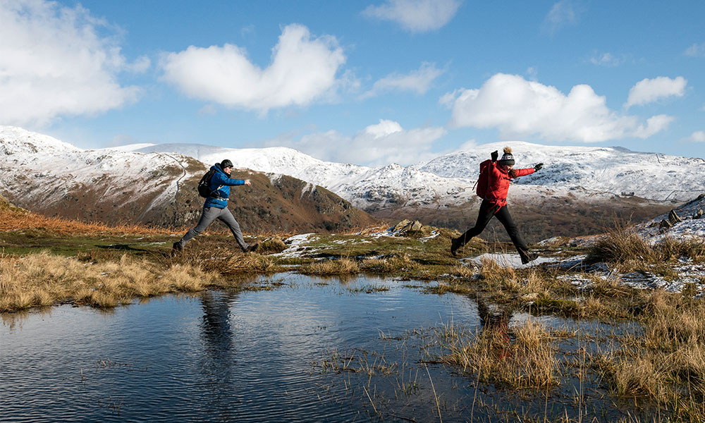 Hikers crossing mountain lake winter 