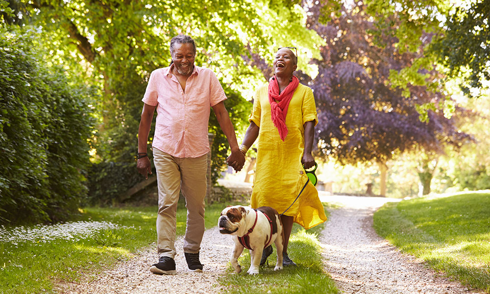 couple walking their dog outside greenspace&nbsp;