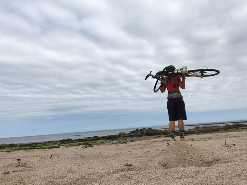 Nicole carrying her bike on the sand